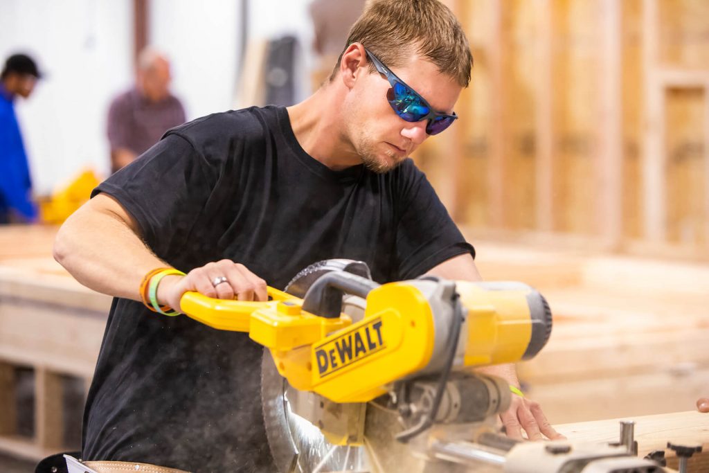 A carpentry student cutting wood with an electric saw