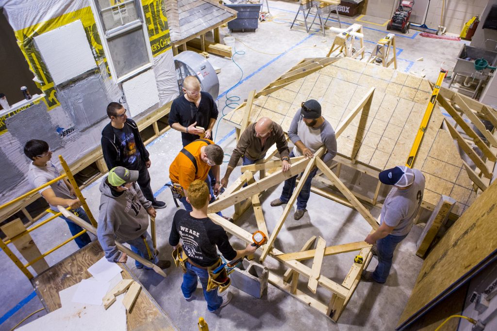 Construction technology students working together to assemble a wooden structure