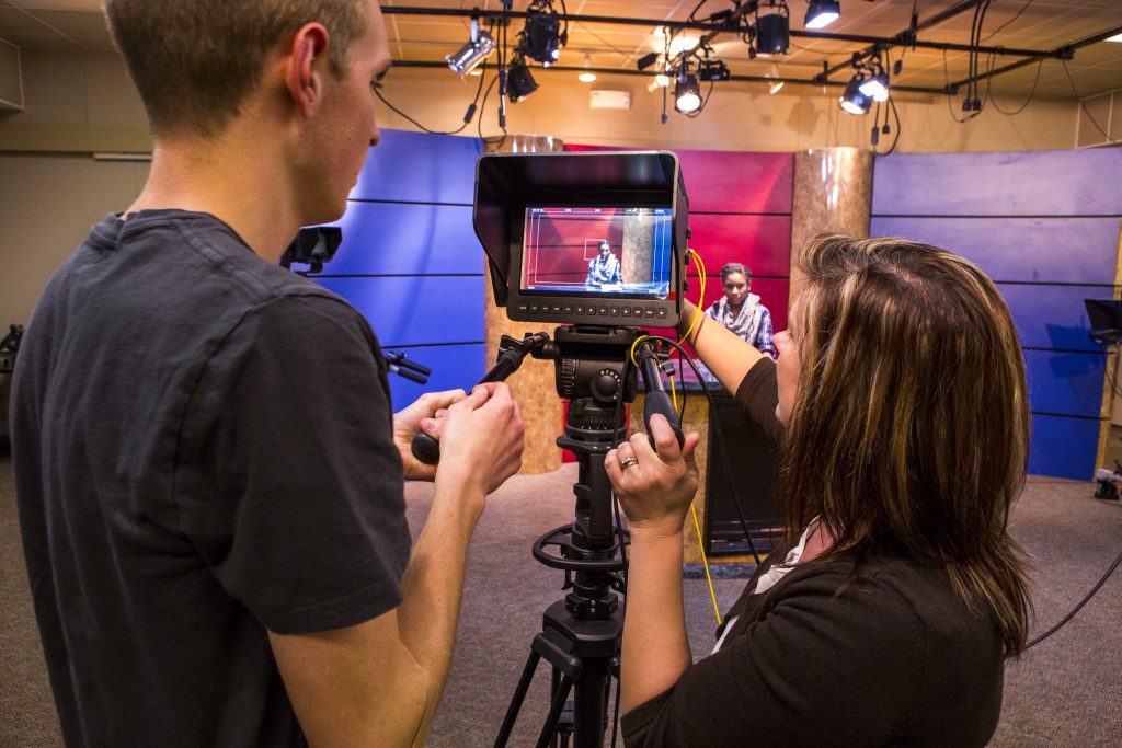 Electronic media production students filming a news broadcast