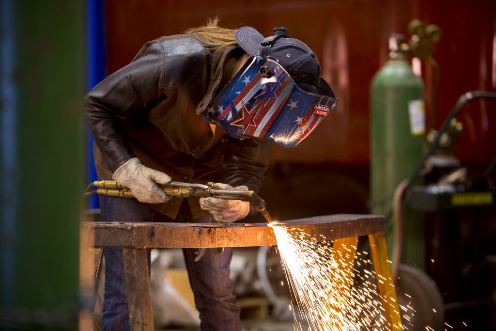 A welding technology student using a welding machine on a piece of metal