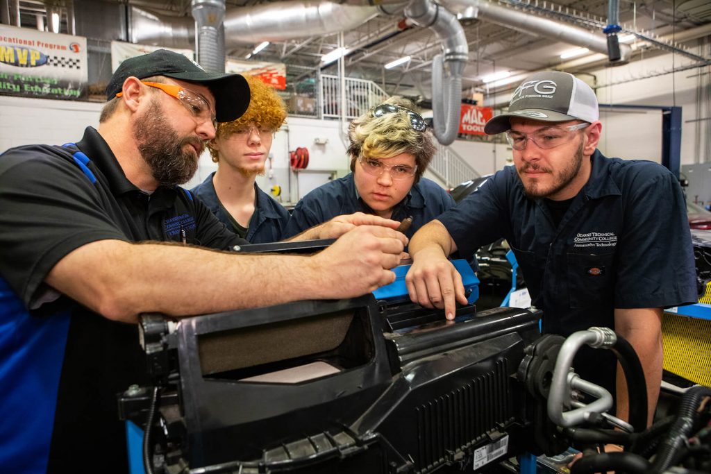 An automotive technology instructor showing students how to work on an engine