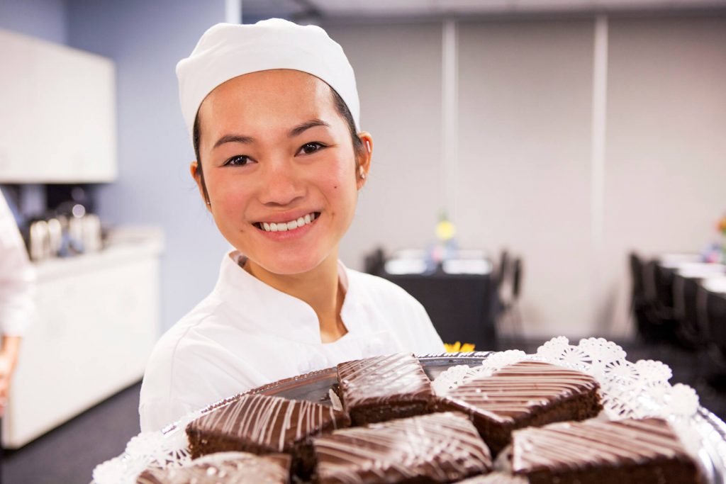 A culinary arts student displaying a plate of chocolates