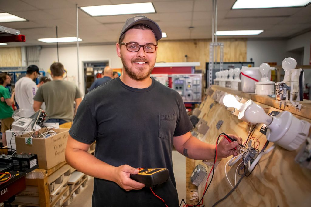 An electrical technician student working with electrical wiring in a classroom lab