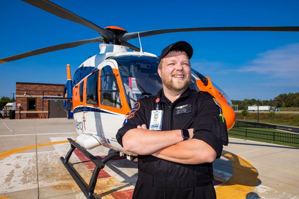 A critical care transport professional standing in front of a medical helicopter