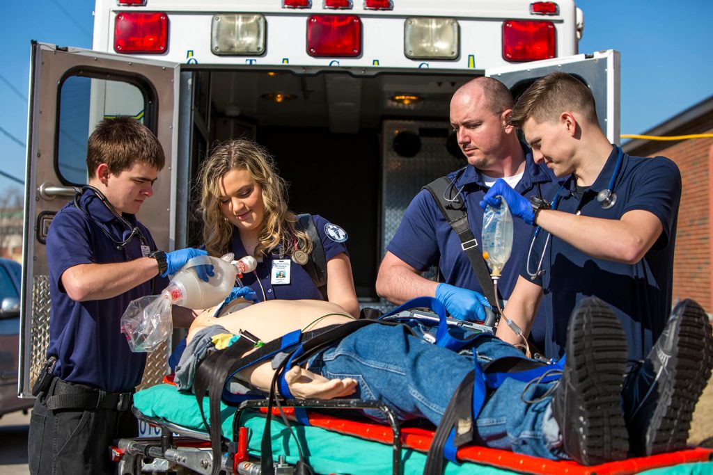 Paramedicine students practicing loading a dummy on a stretcher into an ambulance